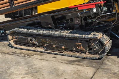 Close-up of Vermeer D36x50 Series II undercarriage, rubber tracks, hydraulic drive, and drill pipe rack side view.