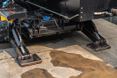 2017 Ditch Witch JT30 hydraulic outrigger stabilizers extended, close-up undercarriage view showing fluid reservoir and hyd lines
