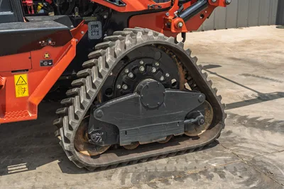 2024 Ditch Witch RT125Q rubber track close-up showing drive sprocket, undercarriage, warning decals, low-hour condition