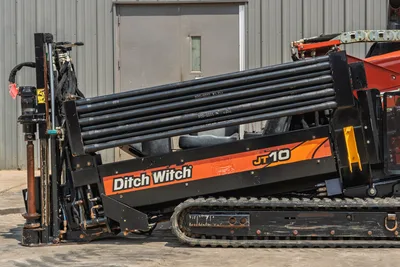 Side view of 2018 Ditch Witch JT10 HDD drill showing drill pipe rack, rubber tracks, and carriage assembly in good condition.