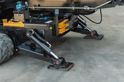 2021 Ditch Witch JT28 hydraulic stabilizer jack and anchor system, close-up showing extended outrigger pad, yellow pipe rack, and hydraulic lines