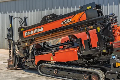 2018 Ditch Witch JT30 All Terrain HDD drill, side close-up showing drill pipe, carriage, vise, hydraulics, and rubber tracks