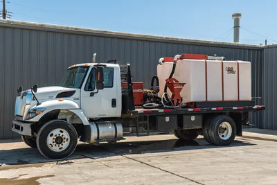 2015 International 7400 flatbed mud truck, driver-side view, white cab, Ditch Witch mud mixing system with poly tank and hopper mounted on flatbed