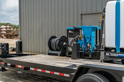 Behnke CBCT2324E-BT-R trailer deck with Straightline SL500 mud mixer, blue pump assembly, corrugated hose reel, and white fluid tank