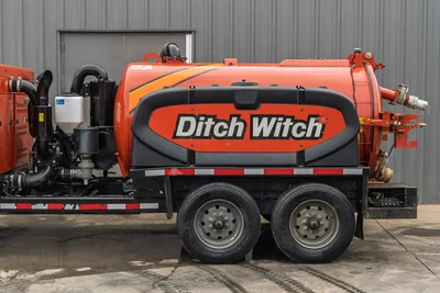 2023 Ditch Witch HX75 mud recycler, tandem-axle trailer, orange vacuum tank, side-mounted pump, hose connections, engine compartment visible