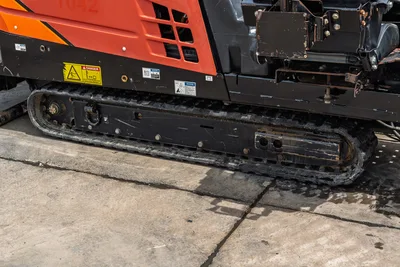 2018 Ditch Witch JT10 rubber track undercarriage close-up, orange bodywork with safety decals, used condition