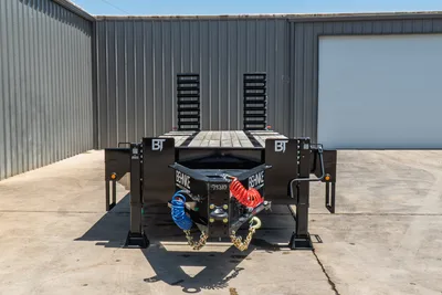 Behnke FB8X30SDPT-40L trailer front view, ball hitch, safety chains, coiled air lines, dual pipe stanchions, wood deck, jack stands visible.