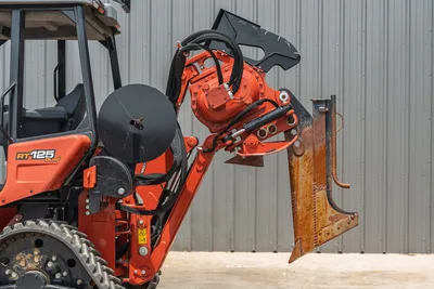 2024 Ditch Witch RT125 Quad trencher boom and digging chain attachment closeup, hydraulic drive motor, wear-worn cutting teeth visible